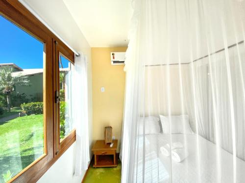 a bedroom with a bed and a large window at Casa Villa Cristian Pé na Areia in Arraial d'Ajuda