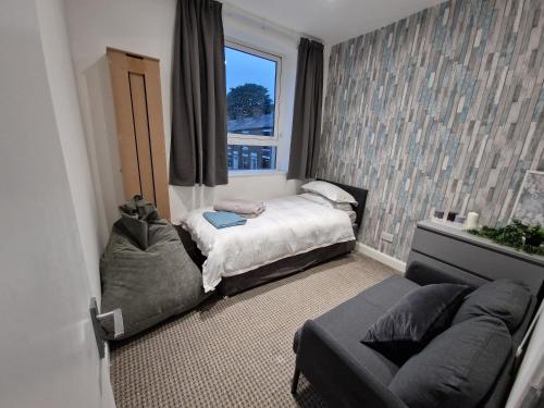 Cette chambre comprend deux lits, un canapé et une fenêtre. dans l'établissement Milne Apartment 2, à Milnrow