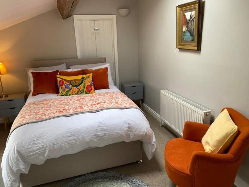a bedroom with a bed and an orange chair at Kitty’s Place, Apartment, Eden Valley, Cumbria in Brampton