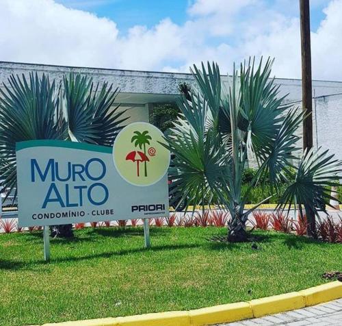 a sign in front of a building with palm trees at MURO ALTO COND CLUBE Bl4 413 in Ipojuca