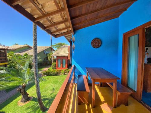 a blue house with a wooden table on the balcony at Casa Villa Cristian Pé na Areia in Arraial d'Ajuda