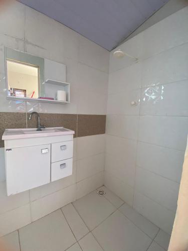 a white bathroom with a sink and a shower at Chalé do Coqueiro in Luis Correia