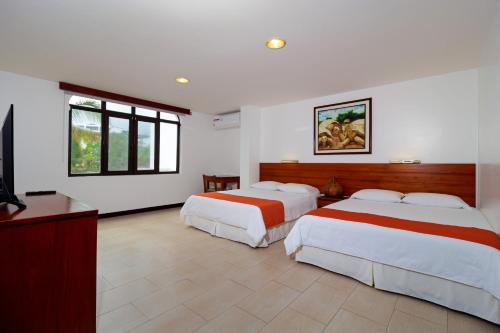 a hotel room with two beds and a television at Galapagos Apartments - Bay View House in Puerto Ayora