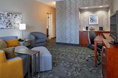 a hotel room with a desk and chairs and a living room at Sonesta Select Indianapolis Carmel in Carmel