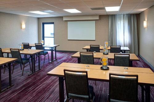a conference room with tables and chairs and a whiteboard at Sonesta Select Indianapolis Carmel in Carmel