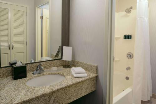 a bathroom with a sink and a mirror and a tub at Sonesta Select Kansas City South Overland Park in Kansas City