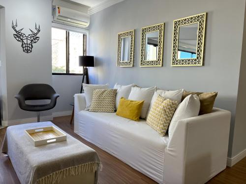 sala de estar con sofá blanco y algunos espejos en Apartamento Decorado Coral, en Balneário Camboriú