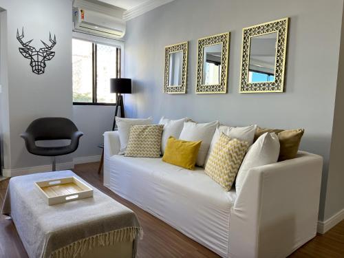 a living room with a white couch and some mirrors at Apartamento Decorado Coral in Balneário Camboriú