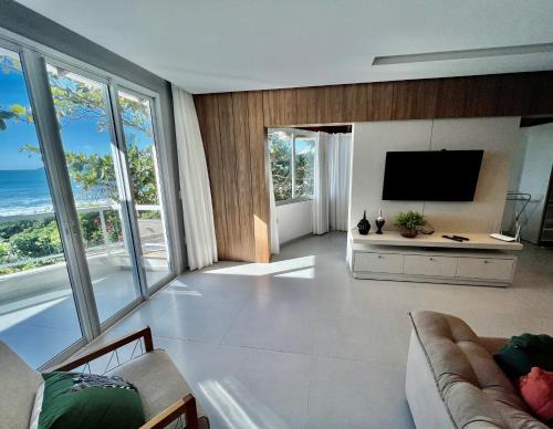 sala de estar con TV y ventanas grandes en Vivencie Esta Experiência Beira Mar, en Bombinhas