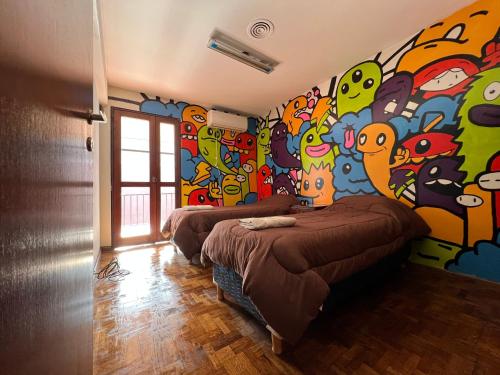 two beds in a room with a colorful wall at Casa Eusebio Blanco con patio parrilla y cochera en el centro de Mendoza in Mendoza