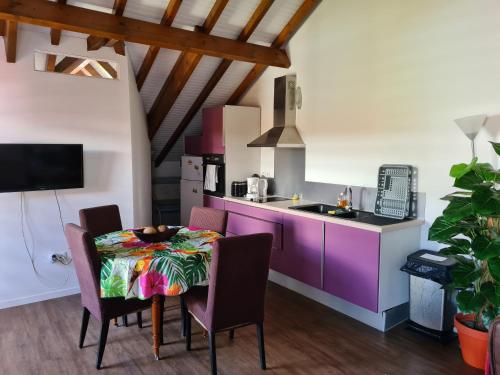 una cocina con mesa y sillas y una cocina con armarios morados. en Cotton residences, en Sainte-Anne