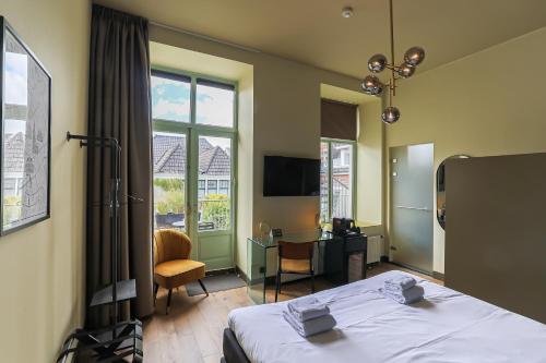 a bedroom with a bed and a desk and a window at Hotel Corps de Garde in Groningen