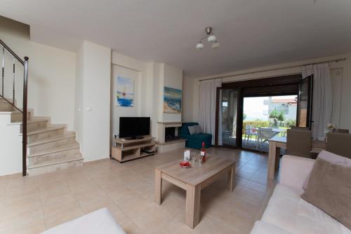 a living room with a couch and a tv at Ariadni -Villas- luxury houses in Kriopigi