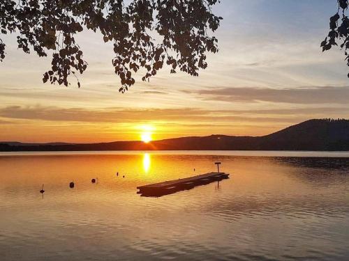 a dock in the middle of a lake at sunset at 6 person holiday home in BOLLNÄS in Bollnäs