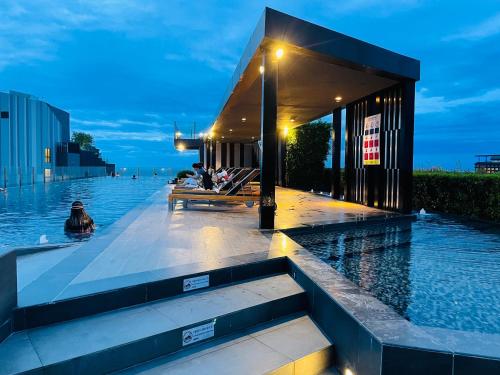 a building with people sitting on benches next to a body of water at The base condo 142 by Pupu in Pattaya Central