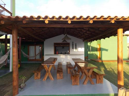 een groep houten tafels en banken onder een paviljoen bij Pousada TAUANE in Caraíva