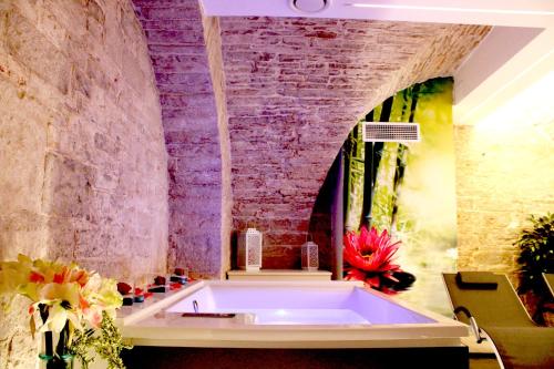 a bath tub in a room with a brick wall at Rubis Relais & SPA in Ruvo di Puglia