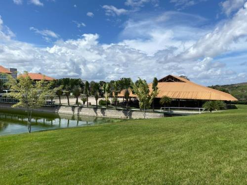 eine Wiese mit einem Gebäude und einem Fluss in der Unterkunft Flat 607 VILLA HÍPICA in Gravatá