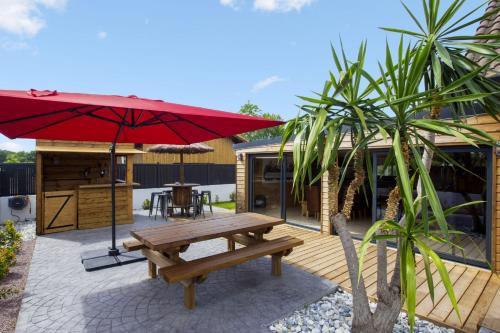 a patio with a picnic table and a red umbrella at L'Atipik - Welkeys in Bénesse-Maremne