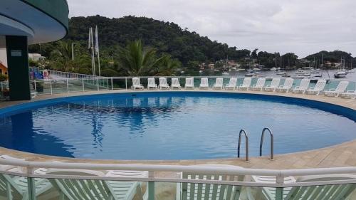a large swimming pool with chairs and a marina at Angra Inn - Praia Grande 318 in Angra dos Reis