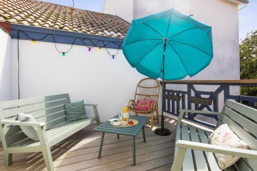 une terrasse avec deux bancs et un parasol bleu dans l'établissement Magnifique maison de ville 3 étoiles avec terrasse - Capbreton - Welkeys, à Capbreton