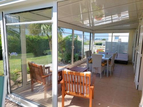 une véranda avec une table et des chaises dans l'établissement Holiday Home in Plouhinec by Audierne Bay, à Plouhinec