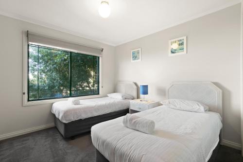 two beds in a room with a window at A Stones Throw in Metung