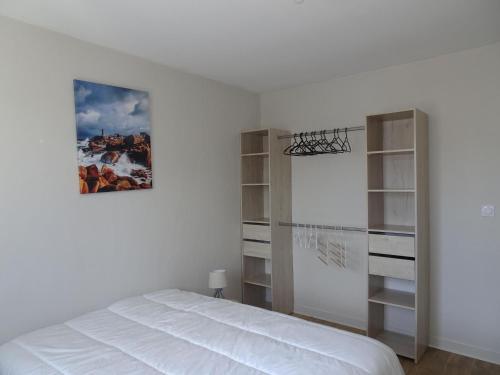 ein Schlafzimmer mit einem weißen Bett und Regalen in der Unterkunft Comfortable Bungalow, Pink Granite Coast in Pleumeur-Bodou