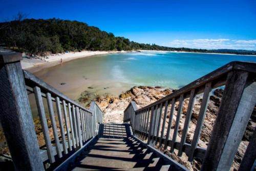 a stairway leading to a beach with a sandy beach at Reflections Byron Bay - Holiday Park in Byron Bay