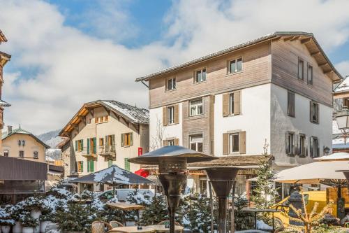 a hotel with tables and umbrellas in front of a building at Appartement de l'Alpage - Welkeys in Megève