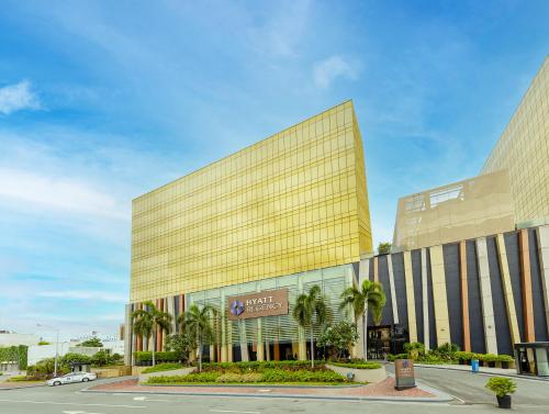 a large yellow building with palm trees in front of it at Hyatt Regency Manila City of Dreams in Manila