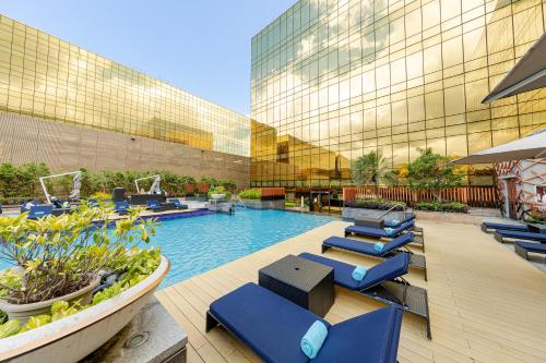 a hotel pool with blue lounge chairs in front of a building at Hyatt Regency Manila City of Dreams in Manila