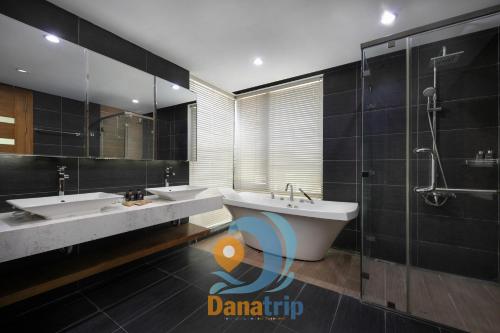 une salle de bain avec deux lavabos, une baignoire et une douche dans l'établissement Deluxe Beach Villas by Danatrip, à Đà Nẵng