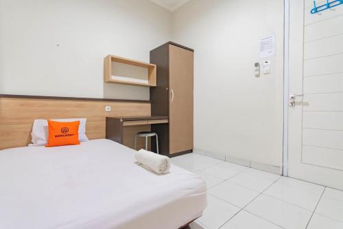 a bedroom with a bed with an orange pillow on it at KoolKost Syariah near Alun Alun Tasikmalaya (Minimum Stay 30 Nights) in Tasikmalaya