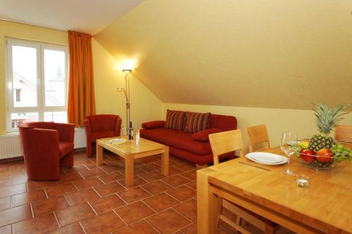 a living room with a red couch and a table at Haus Grete Wohnung 16 in Ostseebad Koserow