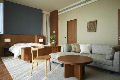 um quarto de hotel com uma cama, um sofá e uma mesa em MUJI HOTEL SHENZHEN em Shenzhen