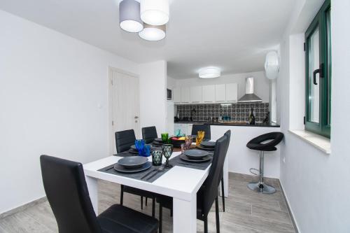a dining room with a white table and black chairs at Villa Mungo in Starigrad-Paklenica