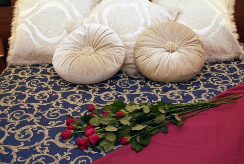 two white pillows sitting on a bed with flowers at Fashion Hotel in Valmontone