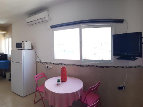 a room with a table with pink chairs and a television at Beau 2 pièces et Beau studio clair en plein centre ville Netanya in Netanya