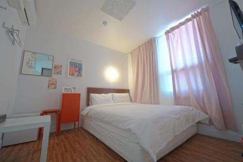 a bedroom with a white bed and a window at Ekonomy Haeundae Hostel in Busan