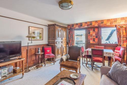 un salon avec une télévision, une table et des chaises dans l'établissement T2 typique et chaleureux avec balcon au coeur de Megève - Welkeys, à Megève