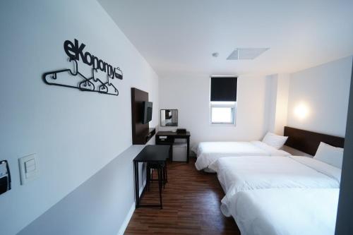 a hotel room with three beds and a desk at Ekonomy Haeundae Hostel in Busan