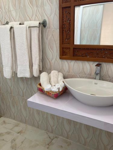 a bathroom with a sink and a mirror and towels at Villa Agung Beach Inn in Lovina
