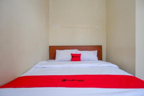 a bed with a red blanket on top of it at RedDoorz Syariah near Terminal Mendolo Wonosobo 2 in Ngasinan