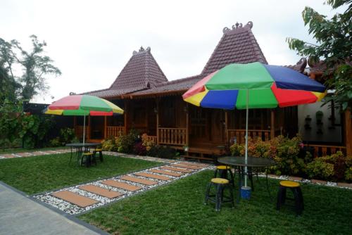 a house with tables and umbrellas in front of it at RedDoorz Syariah near Terminal Mendolo Wonosobo 2 in Ngasinan
