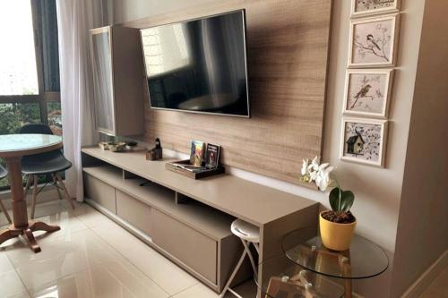 a room with a desk with a television on a wall at Apartamento com estilo e conforto in Recife
