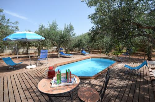 a swimming pool with a table and an umbrella at Cascina degli Ulivi in Castelluzzo