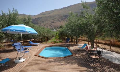 a pool with chairs and a table and an umbrella at Cascina degli Ulivi in Castelluzzo