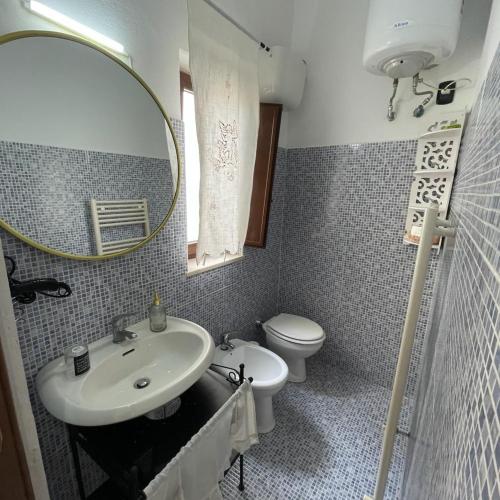 een badkamer met een wastafel, een toilet en een spiegel bij DOMUS LEPRARIUM in Leporano