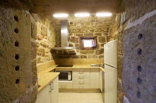 cocina con nevera blanca y pared de piedra en Castell d'Ogern, en Oliana